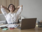 Young happy italian woman with hands behind head relaxing at workplace in home office
